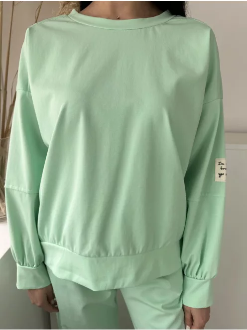 Rugalmas anyagú melegítőszett. Lenge, elöl rövid, hátul hosszú felső, magas, gumis derekú, megkötős nadrággal. (S-XL méretre ajánljuk.)